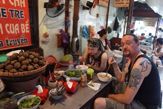 Two tourists are enjoying a dish of "bun oc"